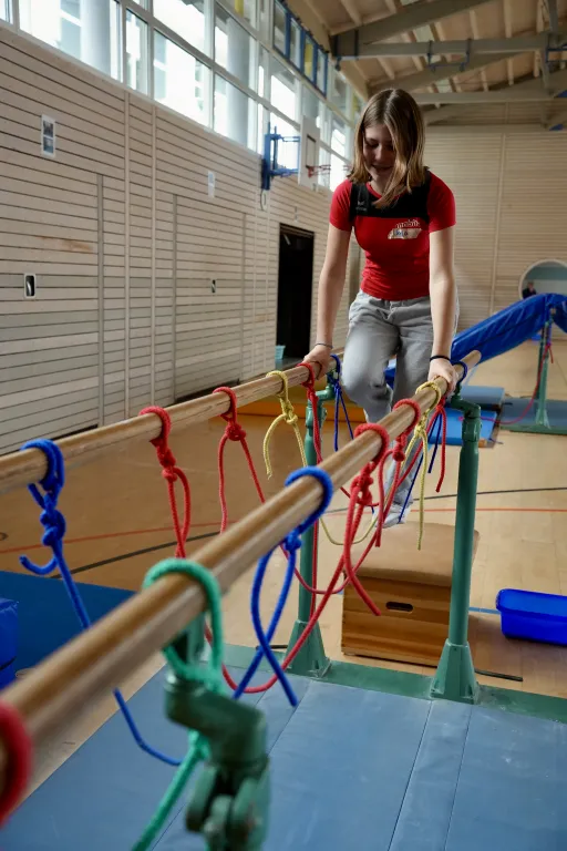 Ein Mdchen hangelt sich ber den Barren.