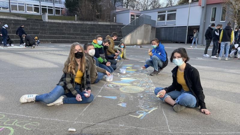Schlergruppe zeigt stolz ihre Zeichnung auf dem Boden