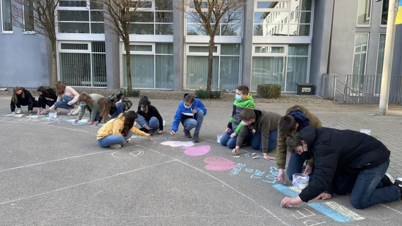 Schüler arbeiten auf dem Boden am Peace-Zeichen