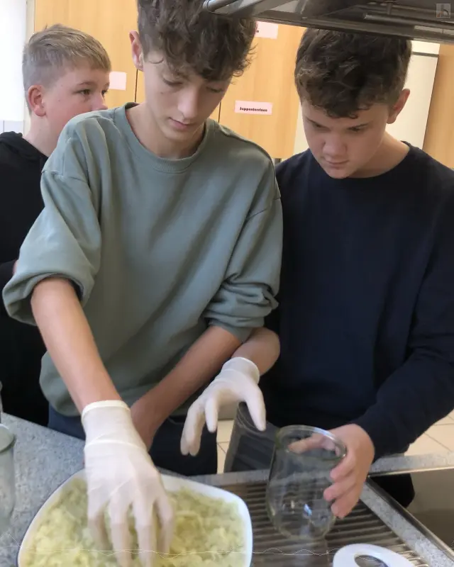 Zwei Jungs befüllen Einmachgläser mit Kraut